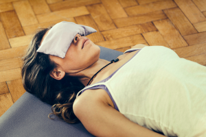 a woman with eye pillow laying on back practising yoga nidra - what is yoga nidra and its benefits
